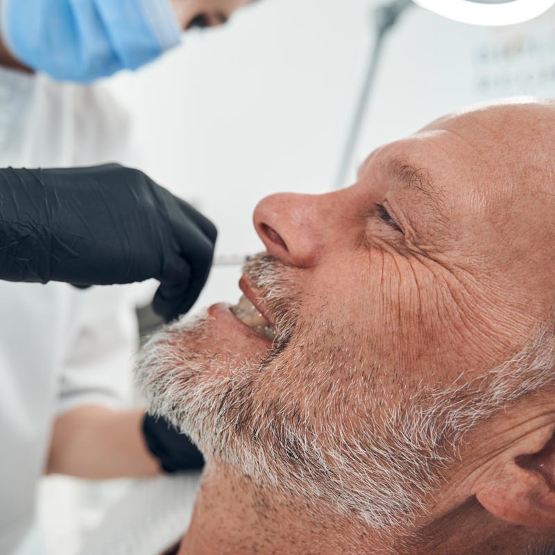 A healthcare professional in gloves performs an ENT procedure on a patient in Surprise, AZ.