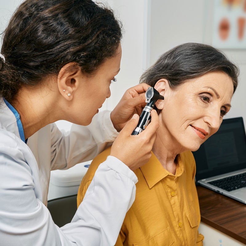 The doctor is checking a lady's ear for ear treatment in Surprise, AZ