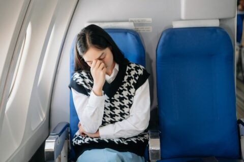 A woman experiencing sinus pain while flying on an airplane in Surprise, AZ