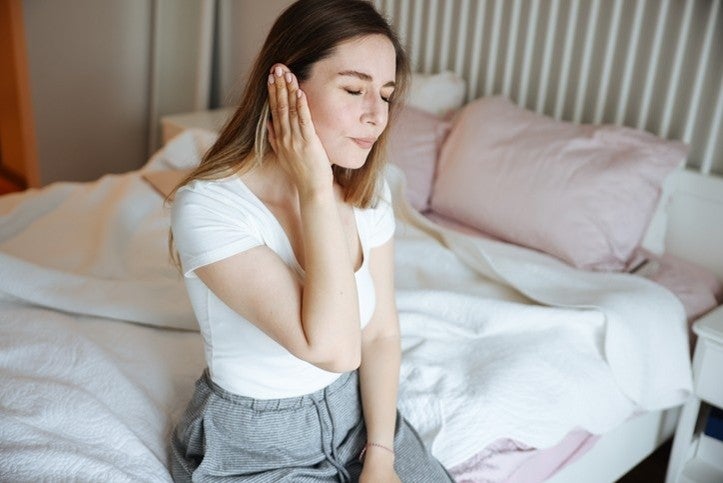 A woman sitting on a bed, hands on her face, reflects pain in Surprise, AZ