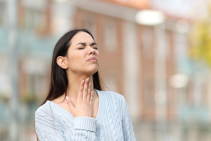 A woman with her hands on her throat, suggesting throat issues, in Surprise, AZ